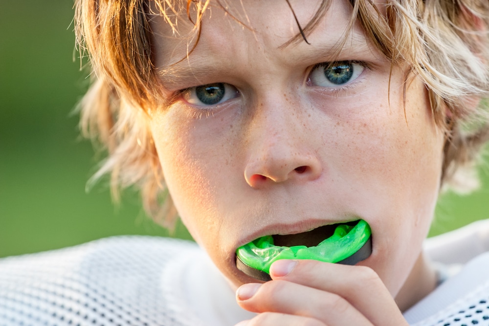 boy putting athletic mouth guard in mouth Athletic Mouth Guards Crawford Leishman Dental dentist in Vineyard Utah Dr. Chris Crawford Dr. Rick Leishman Dr. Matt Fletcher